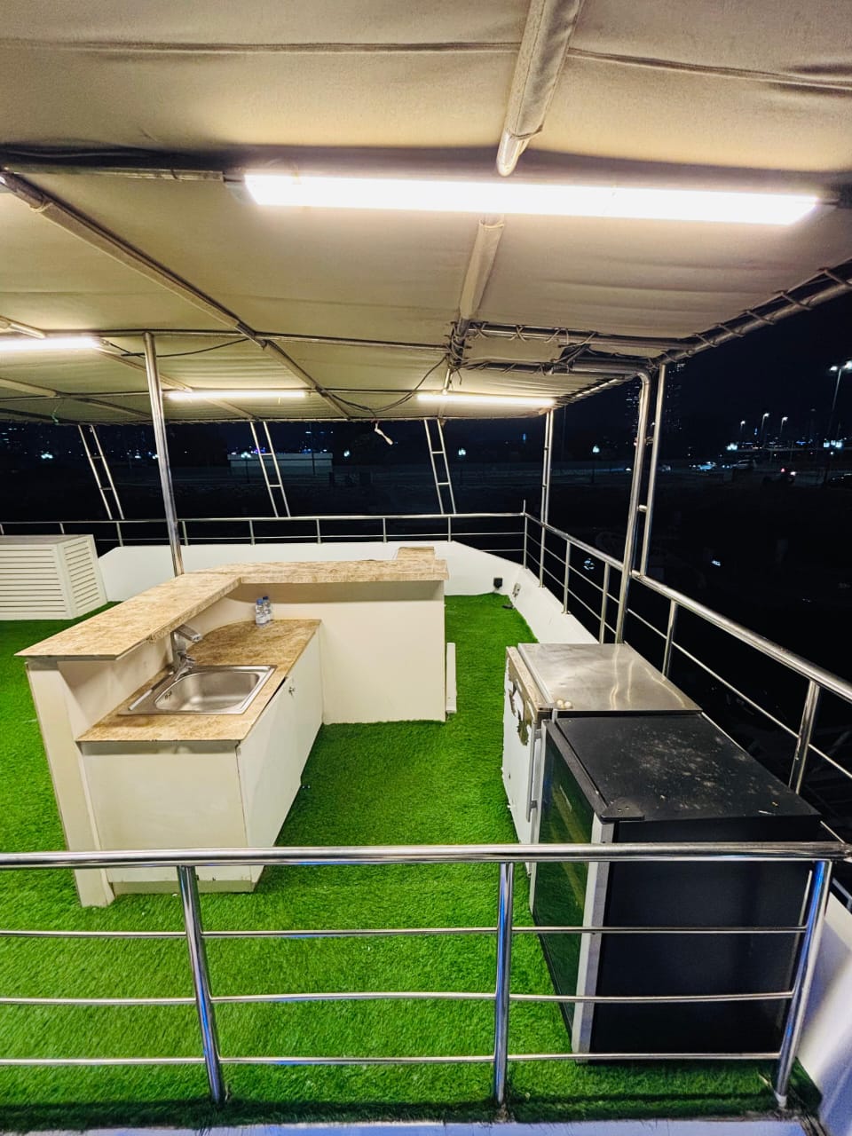 Bar counter with sink and fridge on the covered upper deck at night